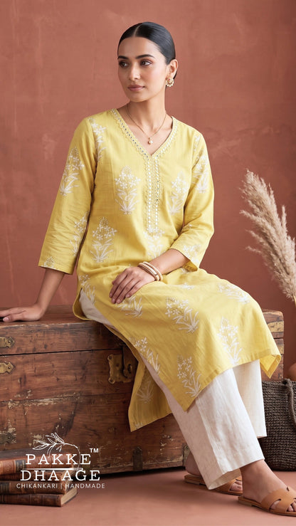 Model wearing Pakke Dhaage lemon yellow floral printed V-neck cotton kurta paired with white trousers.