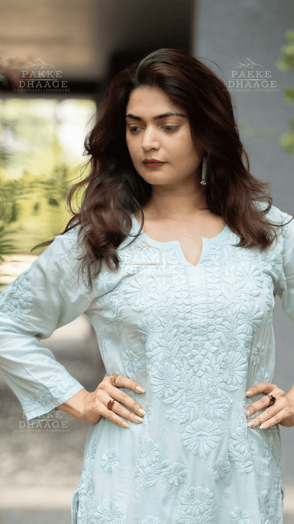 Woman wearing a light blue or aqua chikankari embroidered kurta with a blurred background