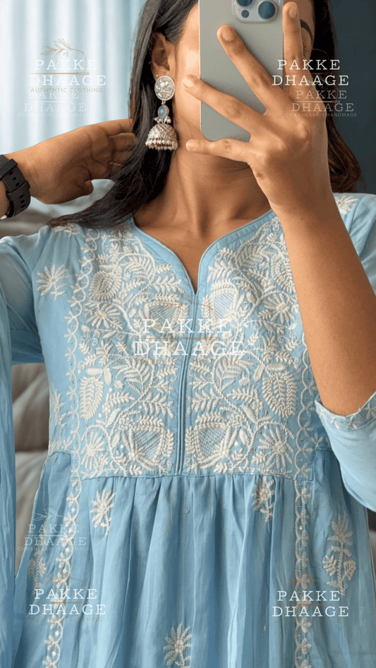 Person wearing a light blue embroidered dress with 'PAKKE DHAAGE' branding.