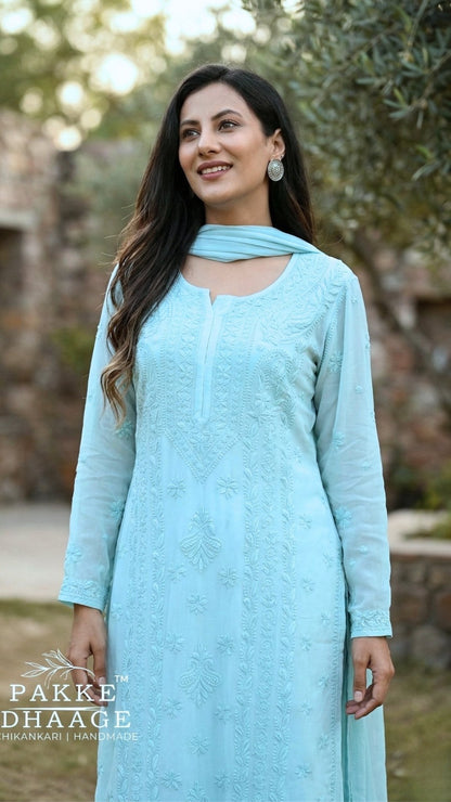 Woman wearing a light blue elegant chikankari outfit with a dupatta, standing outdoors.