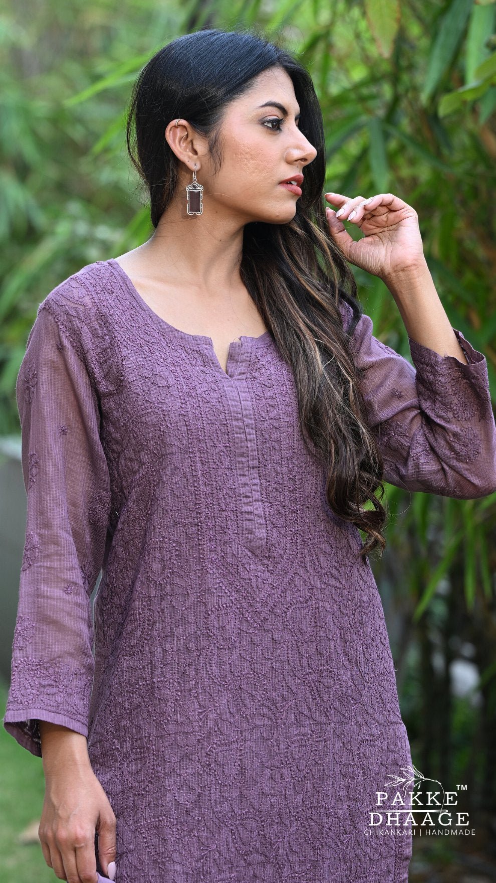 Woman wearing a purple textured Chikankari dress with greenery in the background